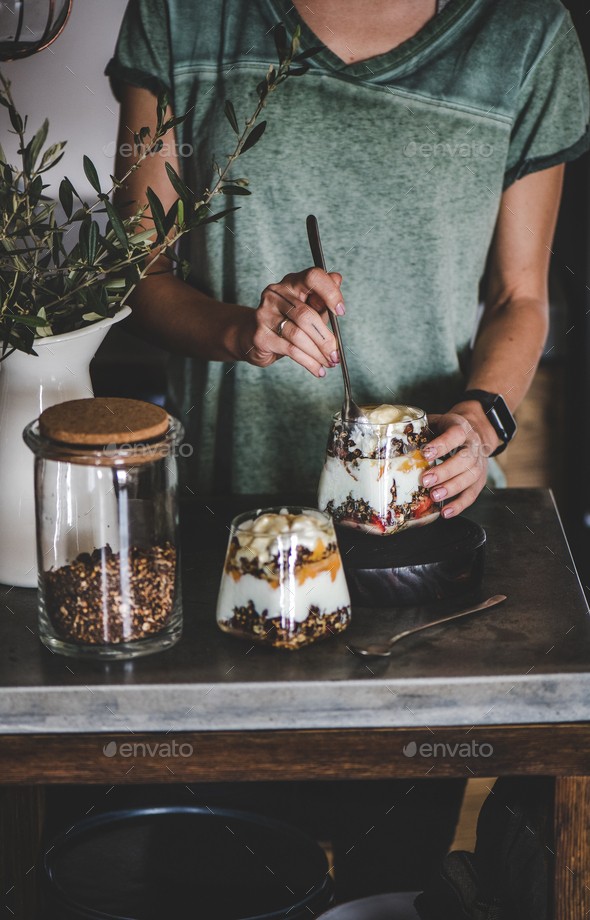 Woman having healthy breakfast with yogurt, granola and fruit - Stock Photo - Images