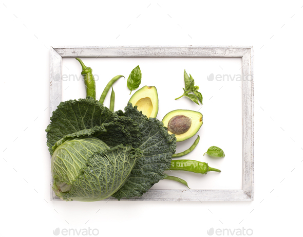 Green vegetables decorating white background and surrounded by wooden frame - Stock Photo - Images