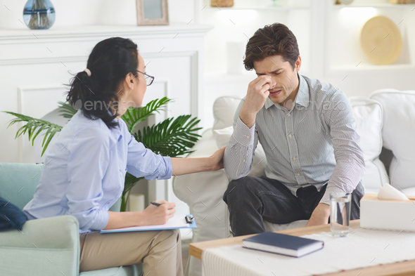 Depressed man feeling drawn at psychotherapist session - Stock Photo - Images