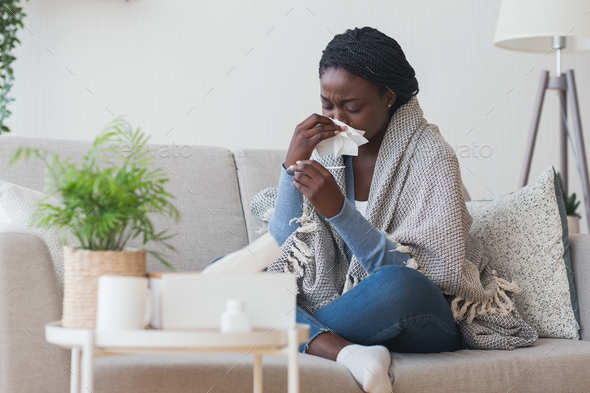 Black girl having flu, blowing nose and checking body temperature - Stock Photo - Images