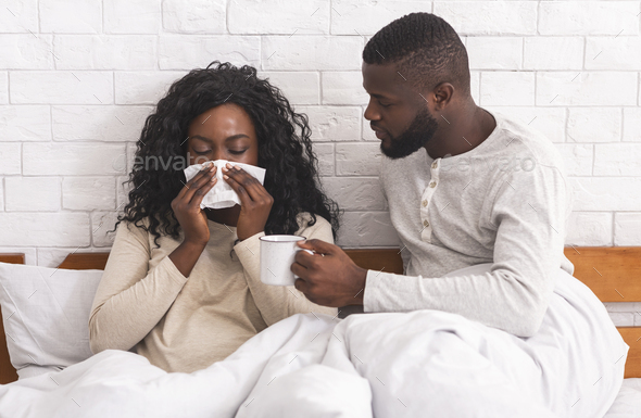Loving husband bringing tea to bed for his ill wife - Stock Photo - Images