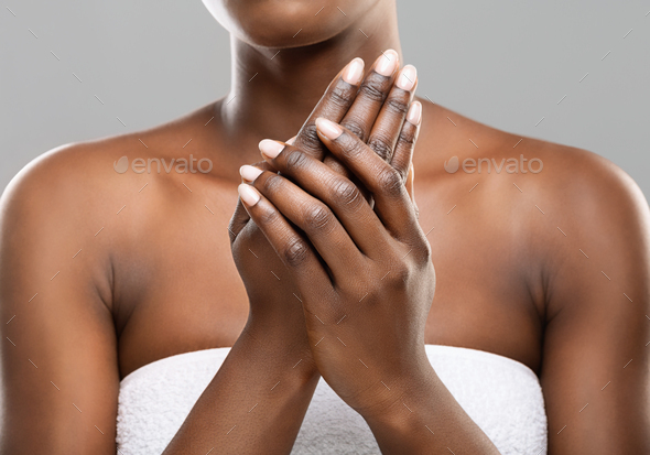 Unrecognizable afro woman applying moisturizing cream to her hands - Stock Photo - Images