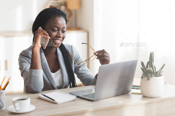 Modern afro business lady using cellphone and laptop in office
