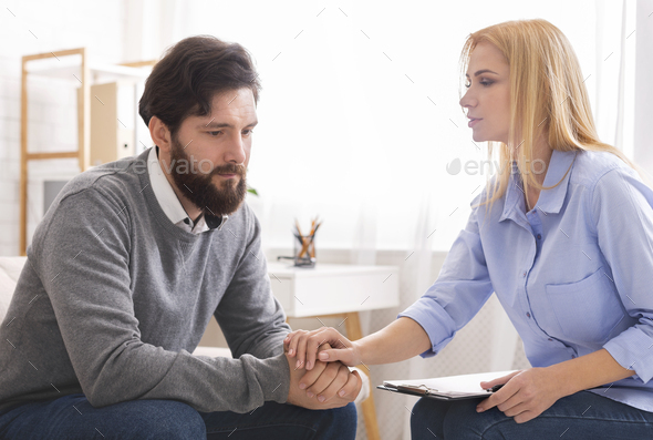 Psychologist comforting depressed man patient at consultation