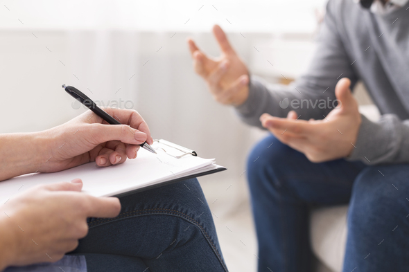 Psychotherapist writing notes, giving diagnosis to emotional man - Stock Photo - Images