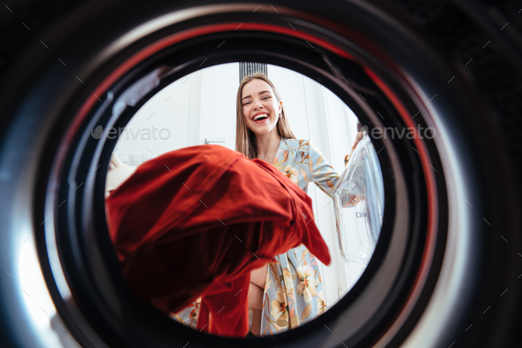 Young woman at home puts the dress in the drying machine