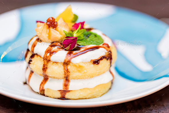 Cottage cheese pancakes or syrniki with cream, fruit jam and flower decoration - Stock Photo - Images