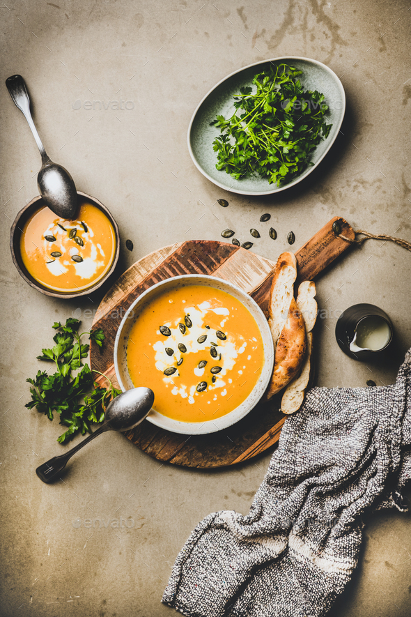 Flat-lay of pumpkin cream soup with seeds, parsley and cream - Stock Photo - Images