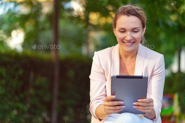 Smiling businesswoman with a tablet in the park. - Stock Photo - Images