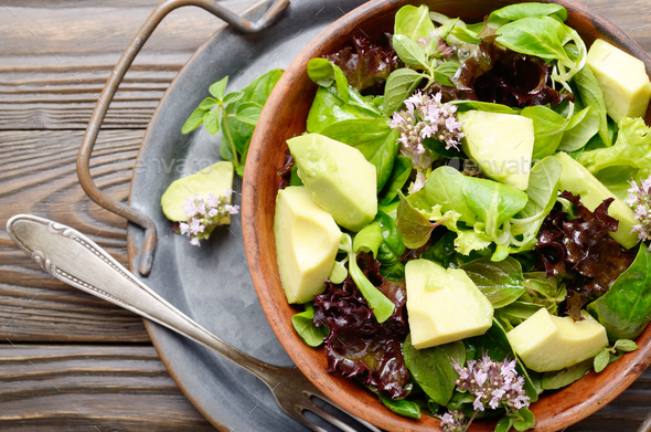 Top view at clay dish with salad of avocado, green and violet lettuce - Stock Photo - Images