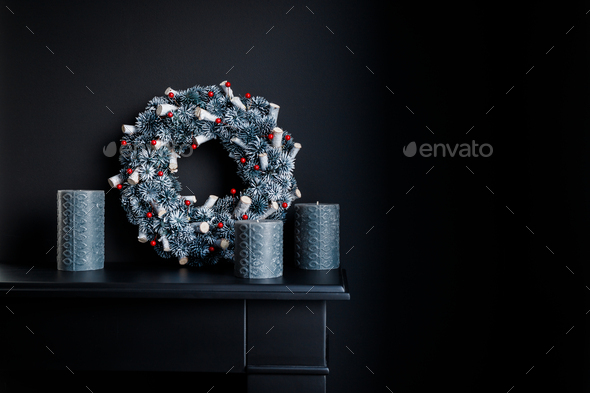 Grey candles and Christmas wreath on a decorative fireplace against black wall - Stock Photo - Images