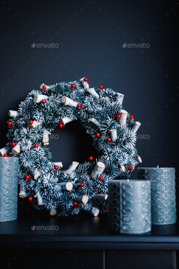 Grey candles and Christmas wreath on a decorative fireplace against black wall - Stock Photo - Images