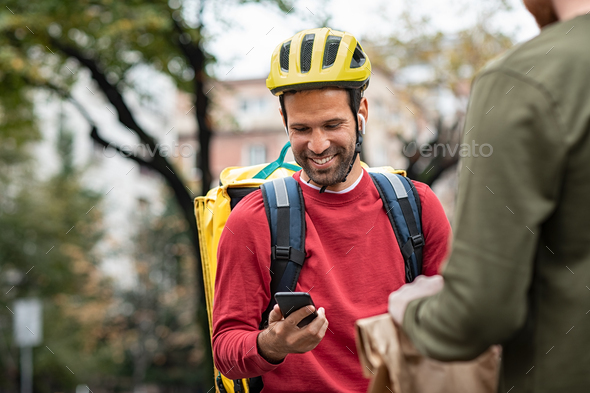 Delivery man checking food order with smartphone - Stock Photo - Images