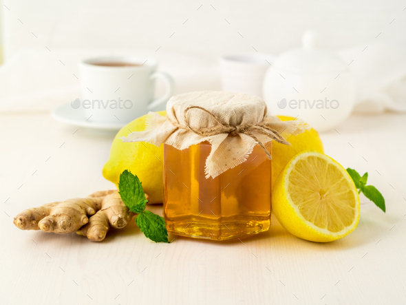 Popular ways to treat a cold - a jar of honey, ginger, mint, lemons on white background, side view - Stock Photo - Images