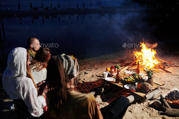 Friends sitting by fire on the beach
