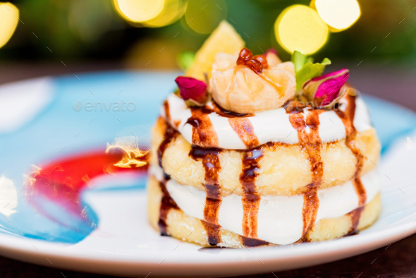 Cottage cheese pancakes or syrniki with cream, fruit jam and flower decoration - Stock Photo - Images