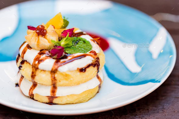 Cottage cheese pancakes or syrniki with cream, fruit jam and flower decoration - Stock Photo - Images