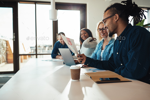 Young African American businessman reading paperwork during an office meeting - Stock Photo - Images