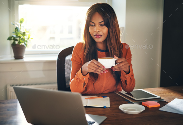 Young female entrepreneur drinking a coffee in her home office - Stock Photo - Images