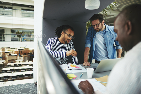 Businessmen discussing work while working in an office pod - Stock Photo - Images