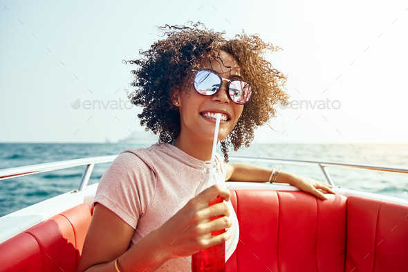 Smiling woman sipping on a drink while out sailing - Stock Photo - Images