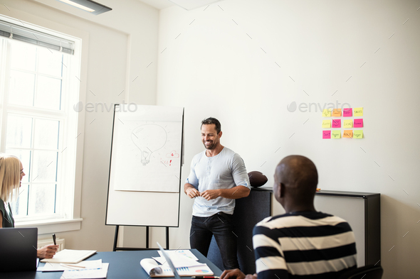 Smiling manager talking with staff during a whiteboard presentation - Stock Photo - Images