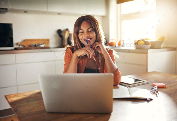 Young entrepreneur working online at her kitchen table at home - Stock Photo - Images