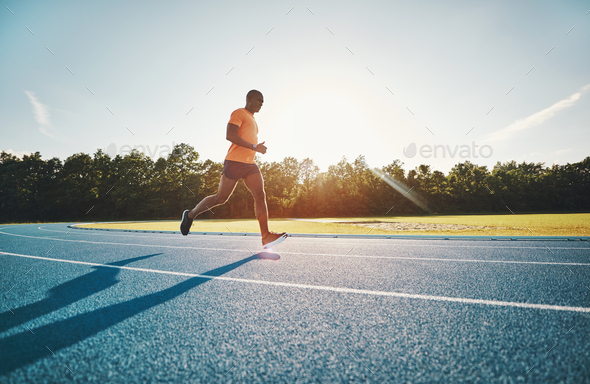 Fit young athlete running along a track in the afteroon - Stock Photo - Images