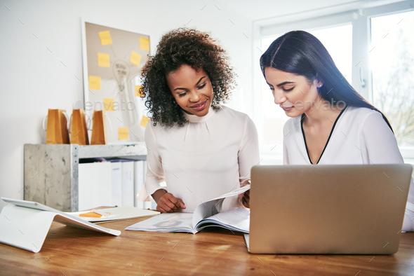 Two young business partners working on paperwork - Stock Photo - Images