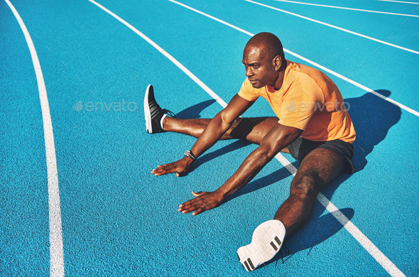 Young runner stretching on a running track before training - Stock Photo - Images