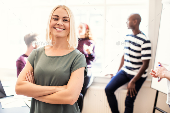 Smiling female designer standing in a bright modern office - Stock Photo - Images