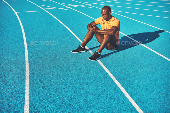 Young African athlete listening to music before a run - Stock Photo - Images