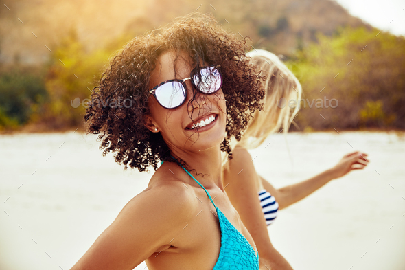 Smiling young woman walking with a friend at the beach - Stock Photo - Images