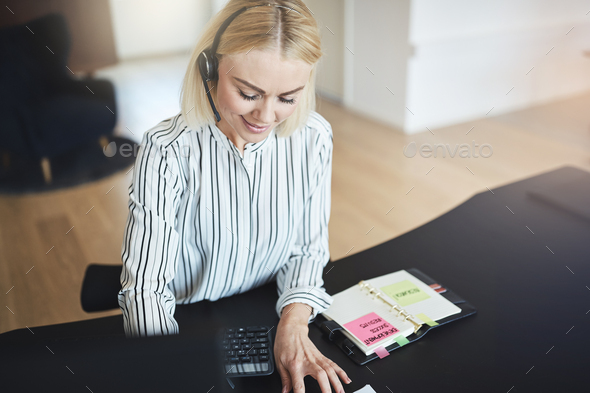 Businesswoman talking with her client on a headset at work - Stock Photo - Images