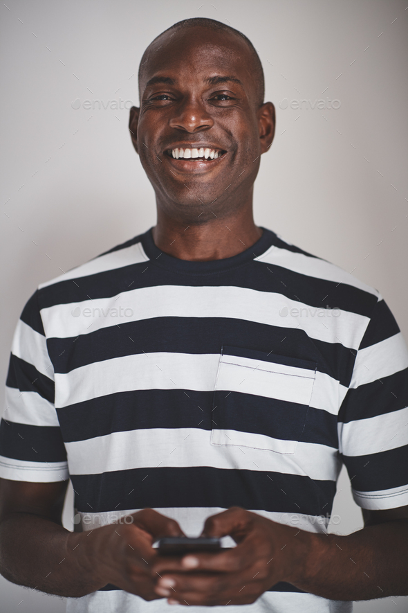 Laughing African entrepreneur using his cellphone against a gray background - Stock Photo - Images