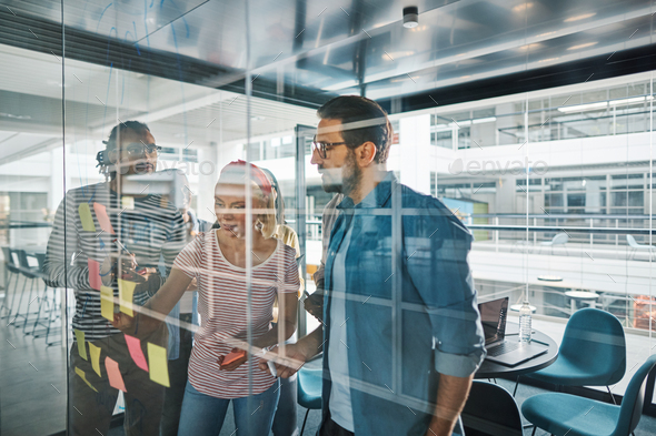 Diverse businesspeople using sticky notes during an office brainstorming session - Stock Photo - Images