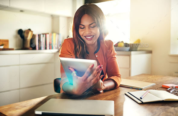 Young female entrepreneur using a digital tablet in her kitchen - Stock Photo - Images