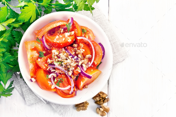 Salad with tomato and walnut in plate on board top - Stock Photo - Images