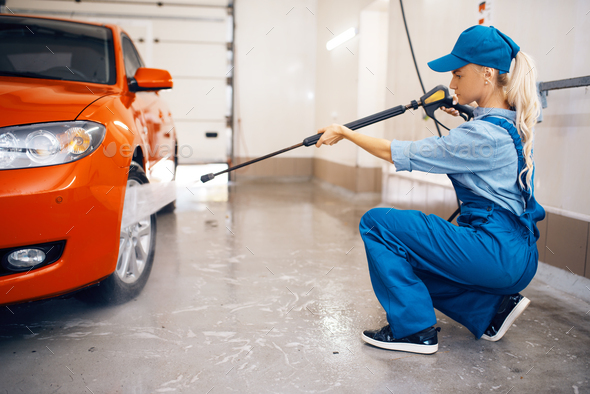 Female washer cleans wheel with high pressure gun - Stock Photo - Images