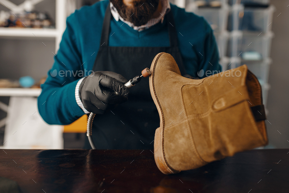 Shoemaker sharpens the shoe sole, footwear repair - Stock Photo - Images