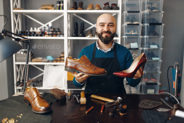 Bootmaker shows repaired shoes, footwear repair - Stock Photo - Images