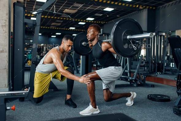 Muscular sportsman and trainer on training in gym - Stock Photo - Images