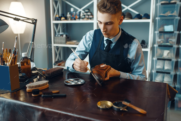 Shoemaker wipes black shoe polish, footwear repair - Stock Photo - Images