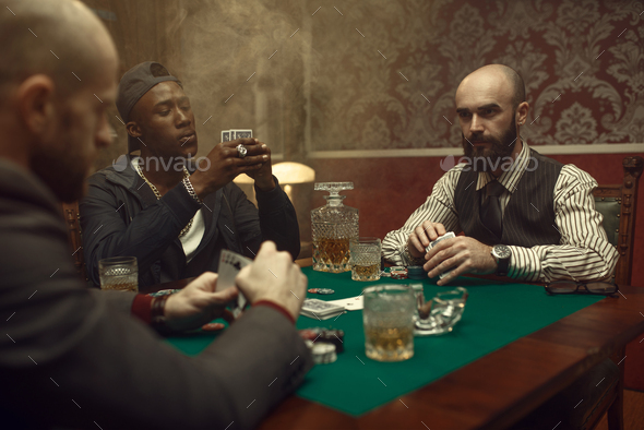 Three poker players with cards playing in casino - Stock Photo - Images