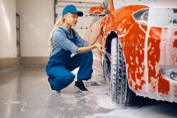 Female washer with brush cleans wheel, car wash