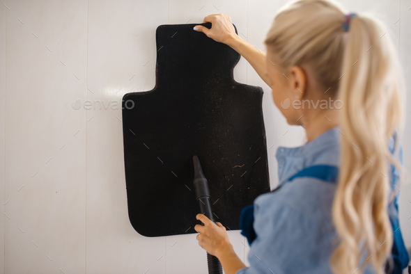 Female washer cleans automobile mats, car wash - Stock Photo - Images