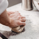 Baker punchs down the dough in the kitchen in the bakery