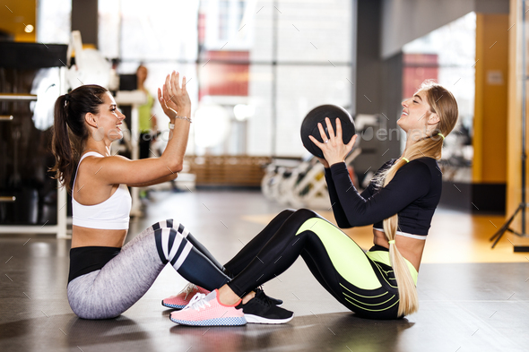 Two young athletic girls dressed in sportswear are doing together sport exercises for press with - Stock Photo - Images