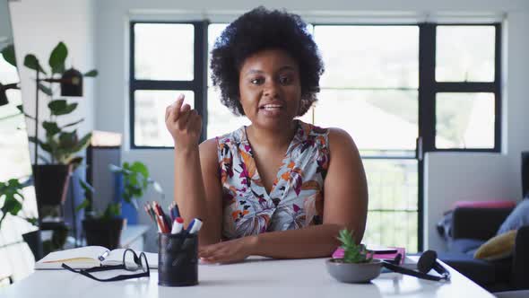 African american female plus size vlogger sitting using laptop having a video chat alt
