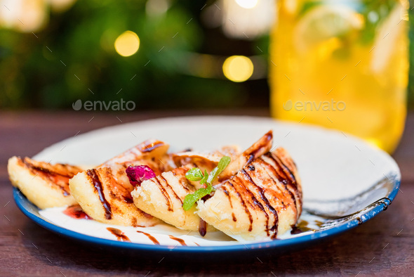 Cottage cheese pancakes or syrniki with cream, fruit jam and flower decoration - Stock Photo - Images